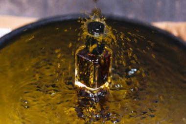 Sarı su arka planında parfümlü bir şişe manzarası. Su damlatılmış Seçici Odaklanma ile