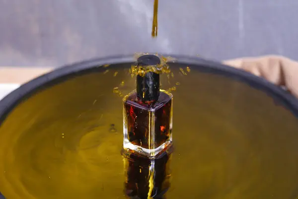 Sarı su arka planında parfümlü şişe manzarası dedi. Damlatılmış suyla