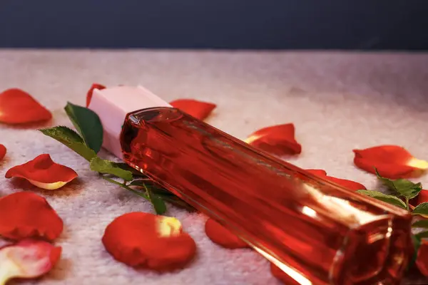 Kırmızı Şişe 'ye yakın plan. Gül yapraklı kadın parfümü.