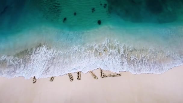 砂浜に書かれたFake_Aweared文字を波で消し 新しい文字のコンセプトビデオを明らかにする — ストック動画