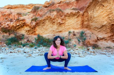 kadın bir plajda yoga yaparken