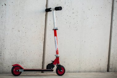 Çocuklar beyaz duvarın yanına park etmiş scooter 'ı tekmeliyor