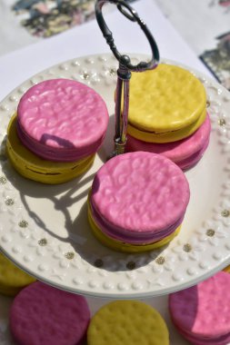 İki katlı porselen tabakta pembe ve sarı kekler, boşluğu kopyala