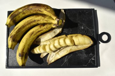 Yakın plan kesilmiş muz kabuğuyla siyah kesim tahta üst görünümde. 