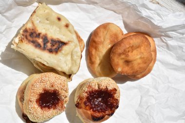 Beyaz kağıt üzerinde çeşitli taze ekmek çörekleri ve çörekler.