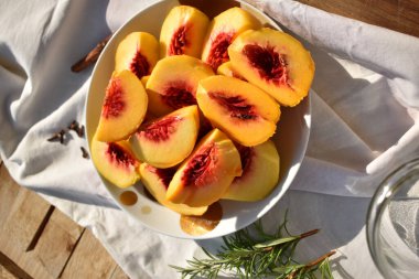 Freshly cut ripe peach slices pitted in plate, close-up view, top view