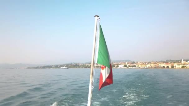 ガルダ湖の観光フェリーに乗って風に優しく振る旗 ボートはラジーズ港を出発し ペシエラ ガルダに向かっている 晴れた夏の日です — ストック動画