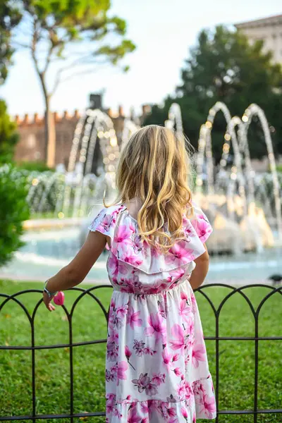이탈리아 베로나의 공원에서 아름다운 드레스 머리와 귀여운 소녀는 카메라로 그녀를 로열티 프리 스톡 이미지