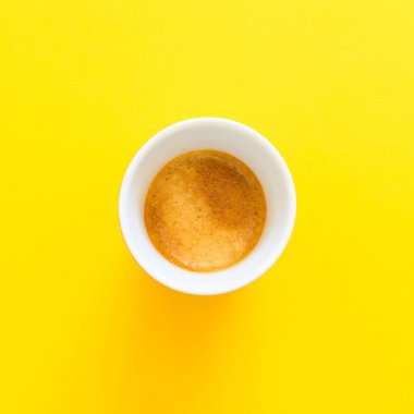 Sarı arka planda küçük bir fincan espresso. Lezzetli, beyaz bardakta taze kahve. Uzayı kopyala.