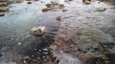 İzlanda 'daki Geysir ve Strokkur gayzerlerinden gelen küçük bir kaynar su deresinin yakınında. Su kameraya doğru akıyor.
