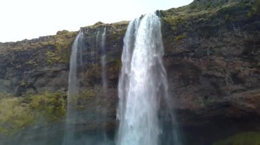 Güney İzlanda 'daki ünlü Seljalandsfoss. Kamera yavaş çekimde aşağı ve yukarı doğru dönüyor. Şelalenin arkasında bir mağara var, böylece insanlar şelalenin arkasında yürüyebilirler.