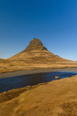Grundarfjordur, İzlanda 'daki görkemli Kirkjufell Dağı' nın güzel manzarası. Dağ birçok film ve TV şovlarında görüldü. Güneşli bir bahar günü, açık mavi gökyüzü
