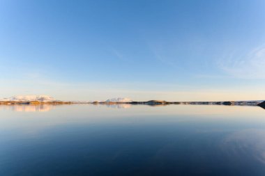 İzlanda 'nın kuzey kesimindeki çok sakin Myvatn Gölü' nün çok güzel yansımaları. Diğer taraftaki dağlar suya yansıyor. Güneşli bir bahar akşamıdır, altın saatin hemen öncesi.