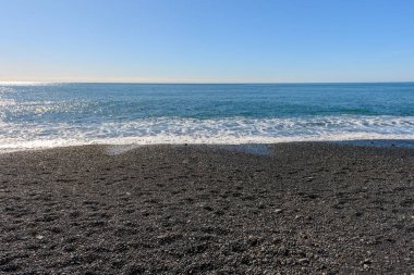 Reynisfjara 'daki boş kumsal İzlanda' daki siyah kumsal. Atlantik Okyanusu 'na bakan kamera. Çakıl kumsalı, su, ufuk ve gökyüzü. Güneşli bir bahar günü ve Atlantik Okyanusu 'ndan gelen hafif dalgalar sahile vuruyor.