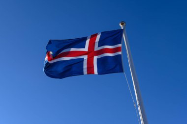 Güçlü rüzgarda dalgalanan İzlanda bayrağı. Güzel, güneşli ama rüzgarlı bir bahar günü.