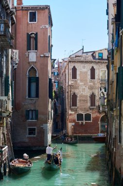 MAY 20, 2017 - VENICE, ITALY: View of narrow canal in Venice, Italy, with gondolas surrounded by picturesque old buildings on spring day with blue sky.