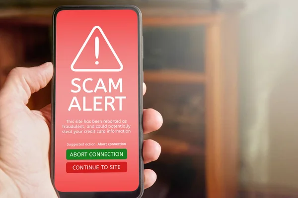 赤い画面で携帯電話を保持し 詐欺警報テキストとサイトはクレジットカード情報を盗むことができるというメッセージと警告アイコンを持つ男性の手の閉鎖 テキストのコピースペース — ストック写真