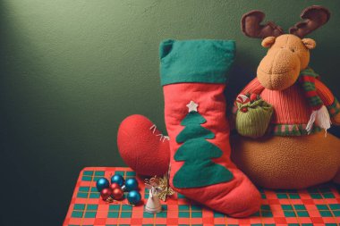 Noel süslemeleri, masada düz duvara karşı duran süsler. Doldurulmuş ren geyikleri, Noel teknesi ve topları ve minyatür melek figürlü Noel arkaplanı. Metin için alanı kopyala.