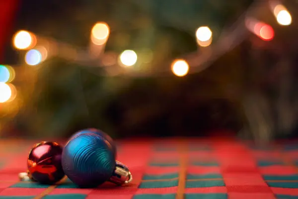 Yatay Noel arkaplanı, yeşil ve kırmızı masa örtülü Noel topları, bulanık Noel ağacı ve ışıklar. Metin için alanı kopyala.