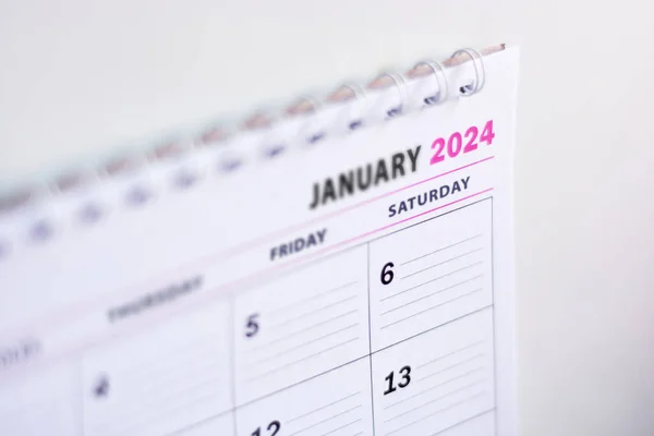 Close up of blank 2024 calendar hanging on fridge with the words January 2024. New year concept, planning and organization. Soft light with narrow depth of field, focus on the number 2024.