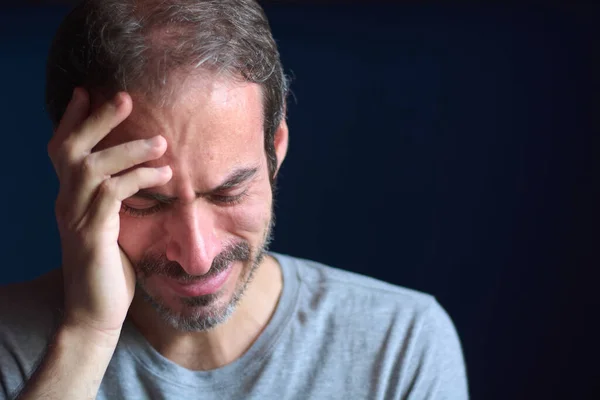 30 yaşında, kısa sakallı, mavi gözlü, başını tutarken ağlayan beyaz bir genç. Depresyon, kayıp ve keder kavramı. Duygusal travma..