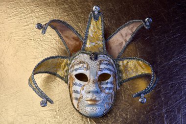 Altın desenli yüzeyde süslü Venedik karnaval maskesi.