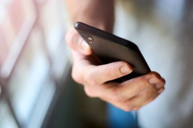 Seçici odaklı ve alan derinliği dar erkek cep telefonunun yakın çekimini yapın. Adam telefon kullanıyor, mesaj yazıyor, arıyor ve internette geziniyor. Metin için alanı kopyala.