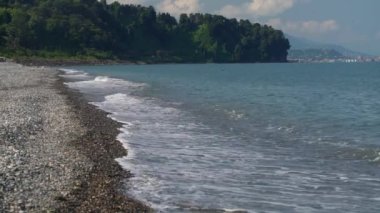 Sea surf on a deserted pebble beach.A cave with stalctites and stalagnites illuminated by artificial light.