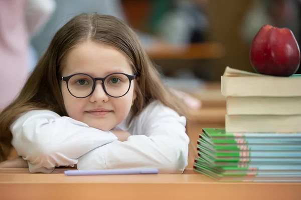 眼鏡をかけた女子学生は机の上で頭を休めた 本とリンゴを持つ教室の女の子 学校に戻る — ストック写真