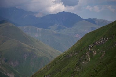 Bulutlar ve bulutlar içindeki dağlar. Sisin içinde yeşil ağaçlar olan bir dağın havadan görünüşü. Yüksek uçurumları, ormanı, gökyüzünü olan güzel bir manzara. dağ vadisi