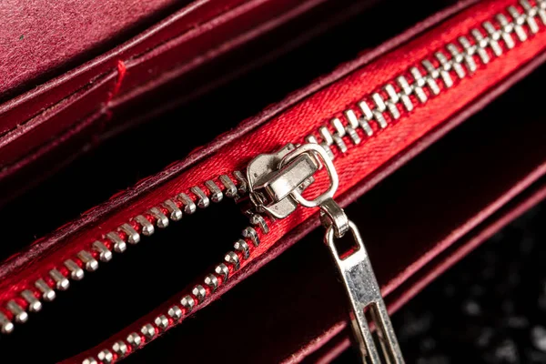 An open zipper on a red leather item or wallet.