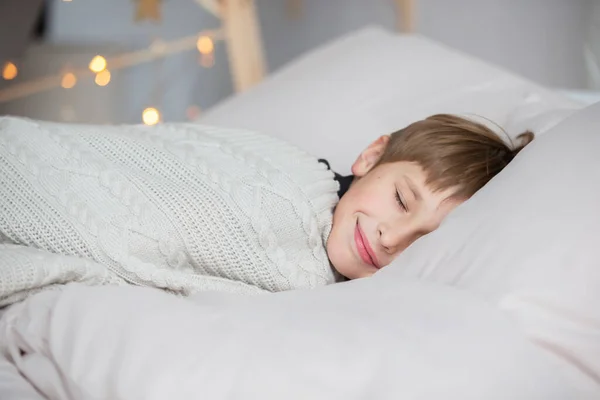 The little boy sleeps and smiles in his sleep, he has a good dream.