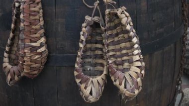 Shoes woven from vines hang on a barrel.