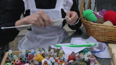 Women's hands knit a woolen fabric from a ball of pink threads. Handmade clothes, needlework.