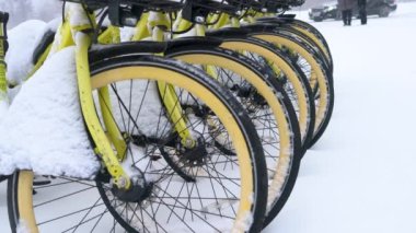 Parked bicycles stand in the parking lot after a snow storm. bicycles covered with snow stand on the street.