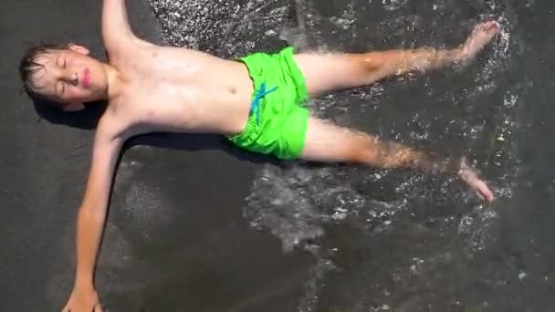 Boy Lies Black Sand Sea Beach — Stockvideo
