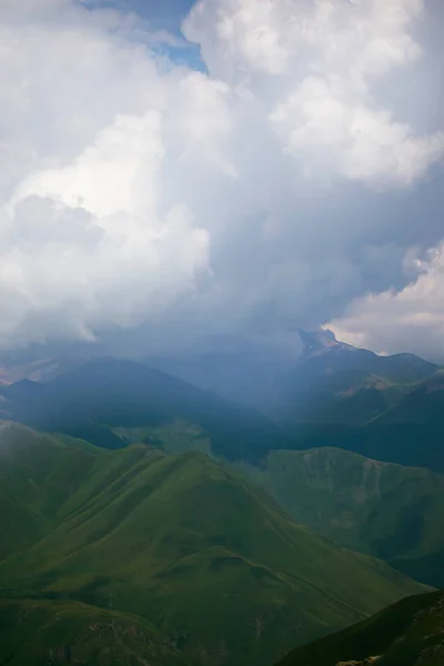Mountains in clouds and clouds. Aerial view of a mountain peak with green trees in the fog.