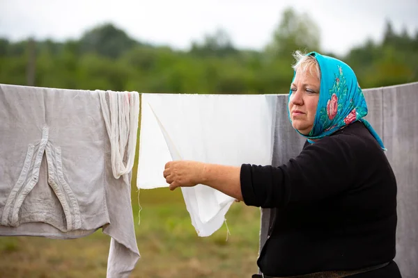 A woman in a refugee camp hangs clothes to dry outside.