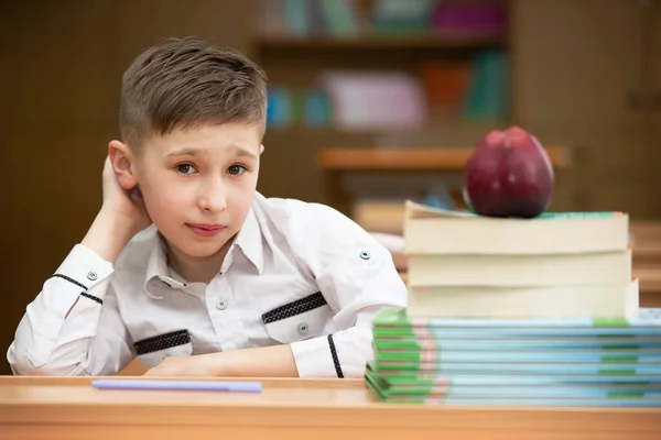 机の上の変な学生 本とリンゴを持って教室にいる少年 中等学校 学校に戻る — ストック写真