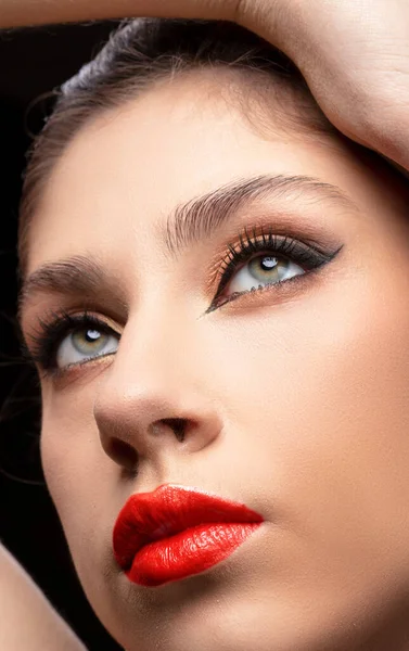 Beautiful young brunette woman face portrait. Beauty model girl with perfect makeup, red lips close-up.