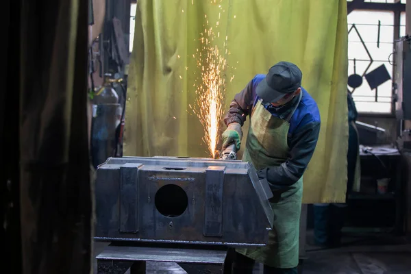 A welder works with metal in a factory shop.
