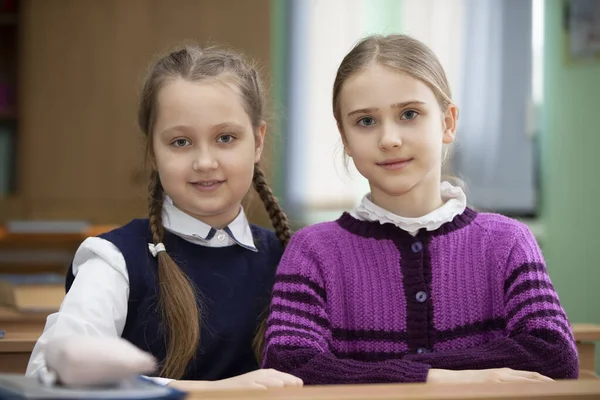 2人の女子学生が教室の机に座ってカメラを見て — ストック写真