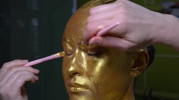 时尚艺术金皮肤女性面对特写肖像 金色的眼睛 嘴唇和皮肤的美丽 模特儿光彩夺目的专业化妆品 — 图库视频影像