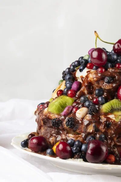 Vertically part of a cake decorated with various fruits and berries.