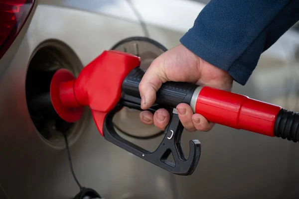 A hand holds a pistol for refueling with gasoline.