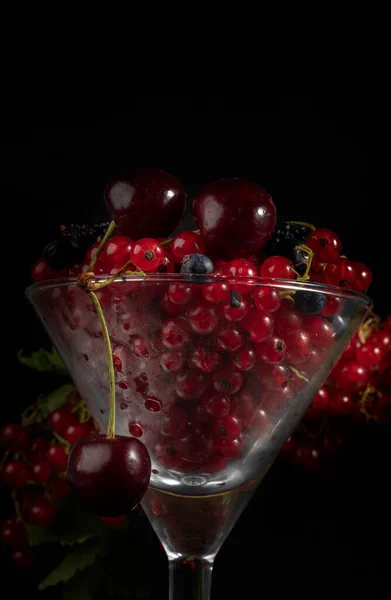 ガラスのゴブレットの暗い背景には チェリーとスグリの赤い果実があります — ストック写真