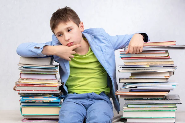 悲しい小学生は本の山の間に座っている 知識を得る 疲れた学生 — ストック写真