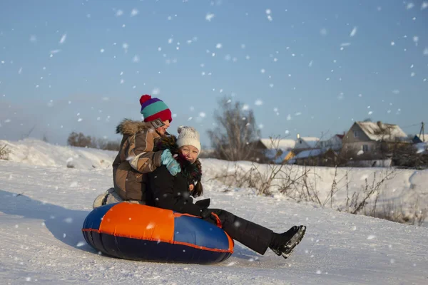겨울날 어린이들은 썰매를 즐겁게 웃는다 소녀가 썰매를 내려가고 있습니다 방학중인 — 스톡 사진