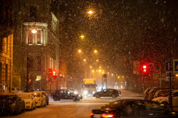 stock image Snow-covered background of the night city with traffic lights and cars.