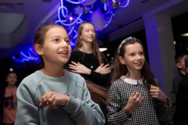 Mutlu çocuklar kulüpteki bir tatil partisinde dans edip doğum günü kutluyorlar..